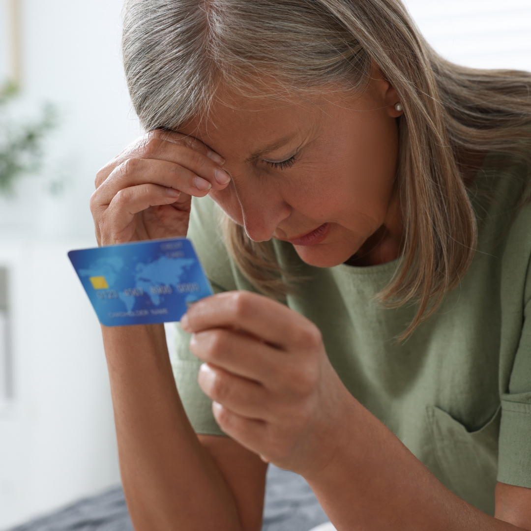 Víctima de estafa revisando su tarjeta – Abogados delito de estafa abogados delito de estafa financiera de una mujer revisando tarjeta de crédito con preocupación